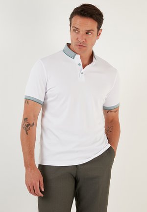 Hvid polo skjorte med en struktureret, teal farvet krave og matchende ærme trim. Har en knapstolpe og glat stof.