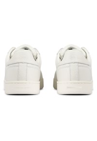 Baskets en cuir blanc avec une finition lisse, bout rond, col rembourré et un logo discret sur le talon. Semelle en caoutchouc au design minimal.