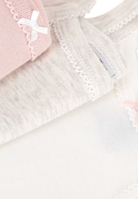 Três peças de algodão macio: uma cor de rosa claro com um laço branco, uma com riscas cinzentas e uma branca lisa, todas com delicada renda na borda.