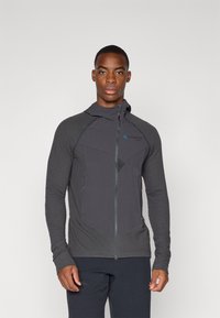 Veste à zip noir avec des panneaux texturés, une capuche et des poches latérales. Présente un motif géométrique et un logo sur la poitrine.