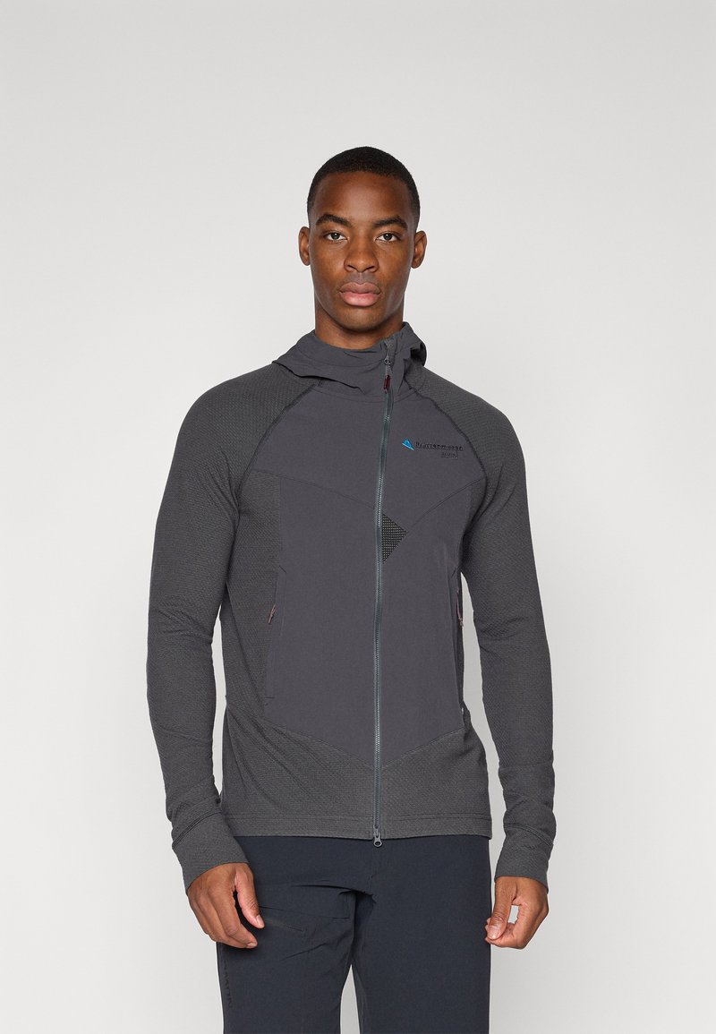 Veste à zip noir avec des panneaux texturés, une capuche et des poches latérales. Présente un motif géométrique et un logo sur la poitrine.