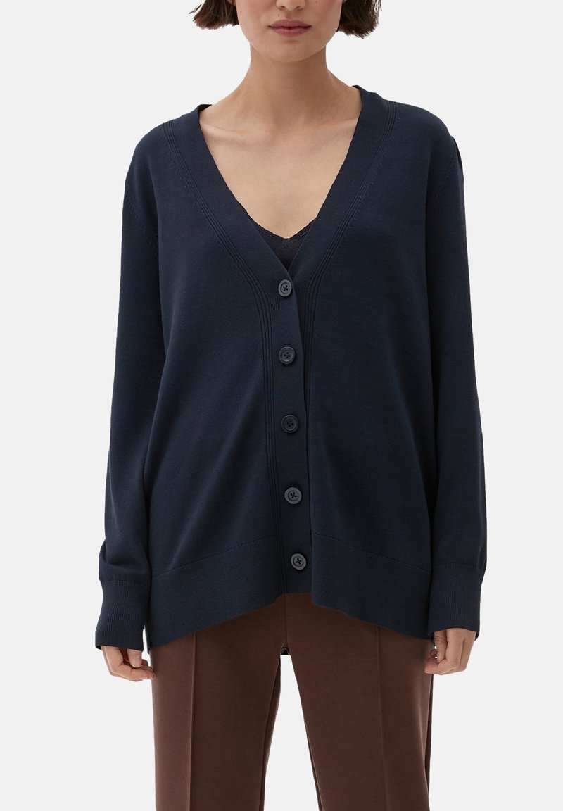 Granatowy kardigan z dekoltem w serek, z przodem zapinanym na guziki, żebrowanymi detalami i luźnym krojem. Wykonany z miękkiego dzianinowego materiału.