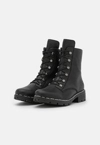 Bottes noires en cuir jusqu'à la cheville avec un laçage à l'avant, quincaillerie en métal argenté, coutures décoratives et semelle en caoutchouc texturé.