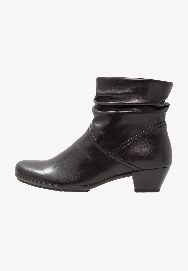 Bottine en cuir noir avec un petit talon empilé et un design supérieur légèrement tombant sur fond blanc.