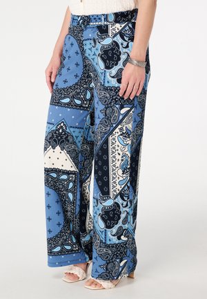 Wijde broek met blauw en marineblauwe paisley-patronen en contrasterende witte accenten. De stof heeft een zachte textuur en een ontspannen pasvorm.