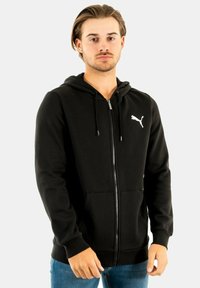 Felpa nera con zip, realizzata in tessuto morbido, con tasca frontale e logo bianco sul lato sinistro del petto, progettata con cappuccio regolabile.