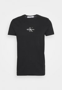 Camiseta de algodón negra de manga corta y cuello redondo. Presenta un logo blanco de Calvin Klein Jeans impreso en el pecho.