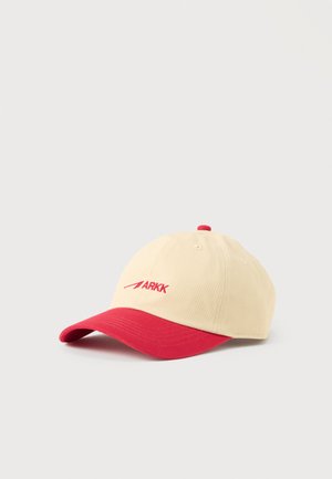 Beige-rote Baseballkappe mit rotem "ARKK"-Logo, das vorne aufgestickt ist, gebogenem Schirm und rotem Knopf oben, auf weißem Hintergrund dargestellt.