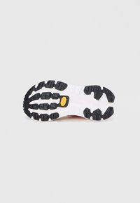 Suola di scarpa in gomma bianca e nera con profondi tacchetti e logo giallo Vibram al centro su uno sfondo chiaro e semplice.