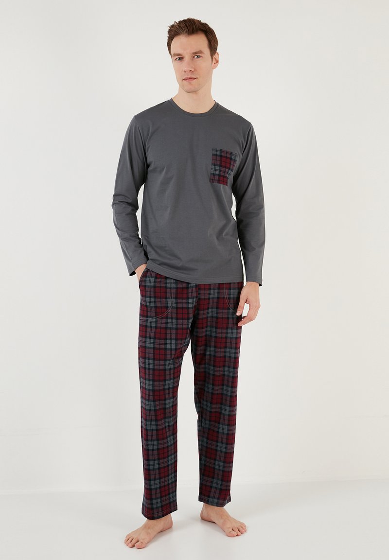 Camiseta de manga larga gris con un bolsillo de cuadros, combinada con pantalones de pijama de cuadros en rojo, azul marino y gris. Sin hardware o acentos visibles.