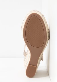 Sandale compensée espadrille beige avec une tige en jute texturé et une semelle brune en caoutchouc, présentant une surface plate et striée pour une meilleure adhérence.