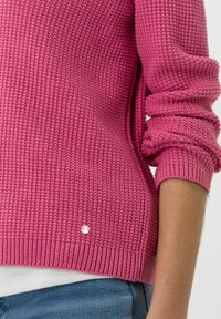 Maglione rosa lavorato a maglia con un motivo testurizzato, polsi a coste e un piccolo dettaglio decorativo con bottone sull'orlo.
