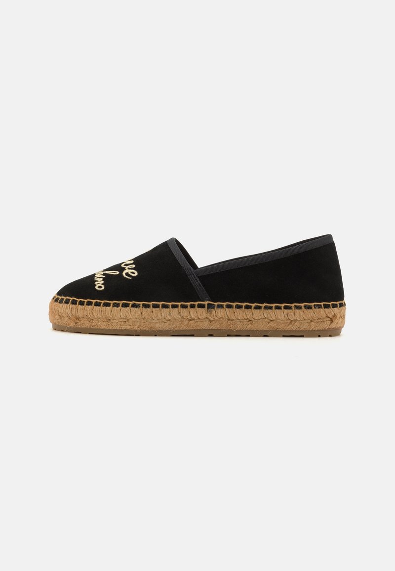 Espadrille noire enfilable avec une semelle en corde et un texte brodé en or sur le dessus, sur fond blanc uni.