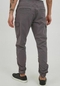 Grijze cargobroek met elastische tailleband en enkelsluiting; voorzien van zij- en achterzakken. Gladde, lichte stof met een relaxte pasvorm.
