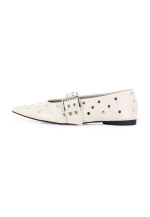 Bailarinas de cuero beige con punta puntiaguda, con tachuelas redondas plateadas y una hebilla decorativa en el lateral. Suela negra.