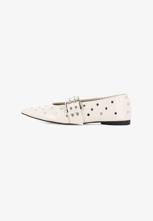 Bailarinas de cuero beige con punta puntiaguda, con tachuelas redondas plateadas y una hebilla decorativa en el lateral. Suela negra.
