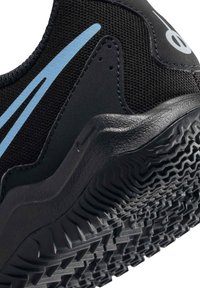 Zapatilla deportiva negra con acentos azules, que presenta una suela de goma texturizada y parte superior de malla, diseñada para durabilidad y tracción.