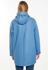 Vandeniui atsparus mėlynas lietpaltis su kapišonu, pasižymintis laisvu siluetu, glotnia tekstūra ir tekstiniu raštu ant apykaklės. Ilgos rankovės ir mygtukai ant riešų.