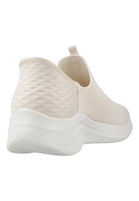 Sneaker slip-on beige chiaro con upper in maglia testurizzata, dotate di un'etichetta di sollevamento, una suola bianca imbottita e un design posteriore con motivo.