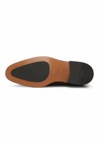 Black leather shoe sole with a smooth, tan midsole and textured black rubber heel. Features a pointed toe and embossed brand logo.