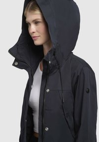 Navy hooded jacket featuring a zip front, snap buttons, drawstrings on the hood, and a patch on the left sleeve. Smooth fabric texture.