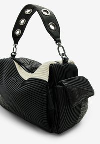 Borsa a mano bianca e nera caratterizzata da materiale a coste, superficie testurizzata e una tracolla nera con occhielli in metallo e dettagli in argento.
