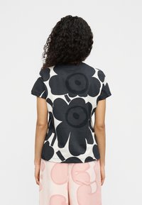 Μαύρο και λευκό T-shirt με φλοράλ πατρόν, κοντά μανίκια και χαλαρή εφαρμογή. Μαλακό ύφασμα, στρογγυλή λαιμόκοψη και περιγραμμένα λουλούδια.