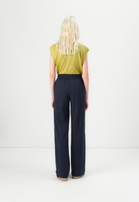 Green, short-sleeved top with ribbed texture paired with loose, navy wide-leg pants, featuring an elastic waistband and no visible patterns.