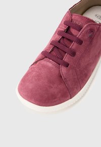 Baskets en cuir bourgogne avec une finition texturée, présentant des lacets ronds, une semelle blanche lisse et un logo subtil sur le côté.