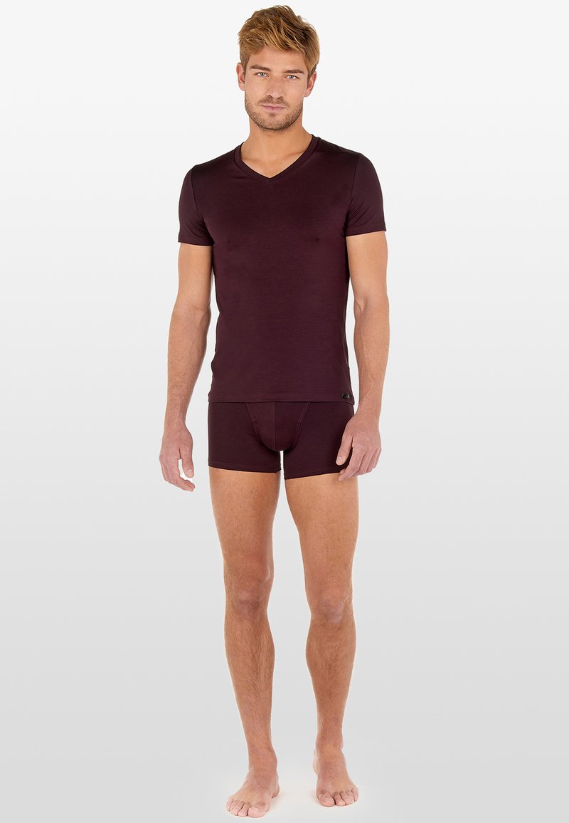Burgundowa dopasowana koszulka typu V-neck w parze z dopasowanymi slipami, oba wykonane z miękkiego materiału, gładkiej tekstury i minimalistycznego designu.
