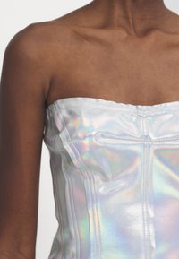 Iridescent bandeau-korsett topp med mjukt, glänsande textur, strukturerade sömmar och subtil regnbågsskimrande yta.