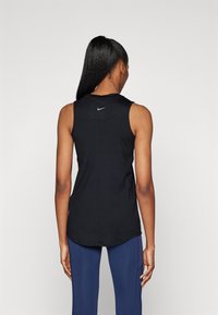 Haut de sport noir sans manches avec un col rond, arborant un logo Nike bleu dans le dos et un ourlet incurvé pour une coupe décontractée.