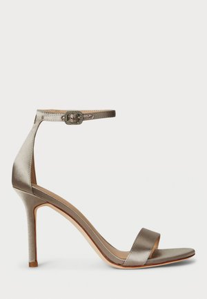 Sandal in satin con tacco alto di colore argento, con cinturino alla caviglia e una fibbia decorativa. Punta aperta e design slanciato e sinuoso.