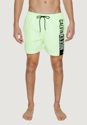 Pantaloncini da bagno verde chiaro con il logo nero "CALVIN KLEIN" sul lato, cintura elastica e cordoncino regolabile. Il materiale appare liscio.