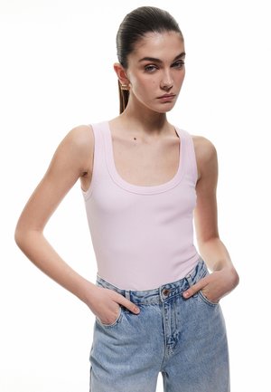 Vaaleanpunainen ribbipinta tanktoppi, jossa on pyöreä pääntie, yhdistettynä korkeavyötäröisiin vaaleansinisiin farkkuihin. Minimalistinen muotoilu, istuva silhuetti.