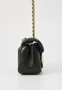 Sac à main en cuir noir avec un design matelassé, un haut arrondi, une bandoulière en chaîne dorée et des détails en matériel doré sur le côté.