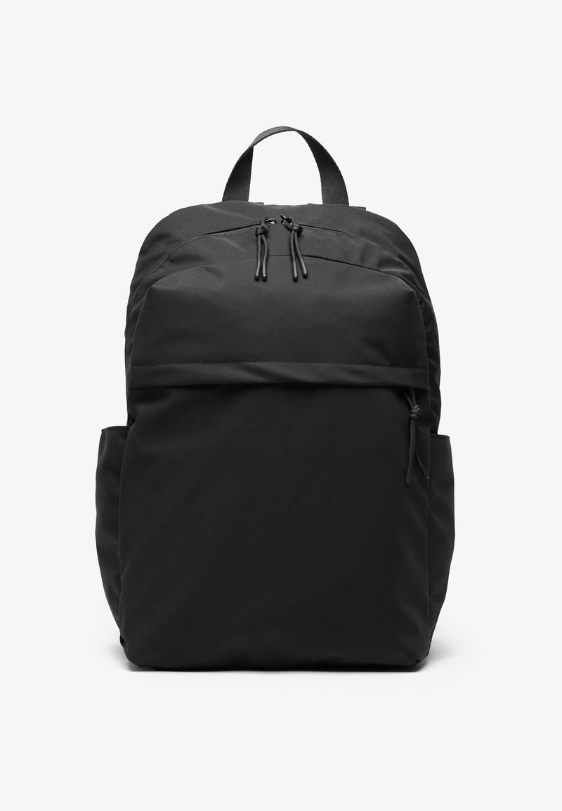 Rucsac negru din material textil, cu fermoare duble, curele umplute și buzunar frontal. Are buzunare laterale din plasă și un design elegant, minimalist.