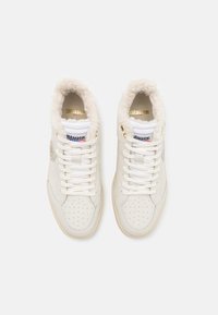 Zapatillas altas blancas con un cuello suave y esponjoso, caja de punta perforada, acentos dorados y diseño con cordones. Logo en el lateral.