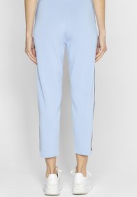 Jasnoniebieskie, krótkie spodnie z żebrowanej tkaniny o gładkiej fakturze, z kontrastującymi ciemnymi paskami po bokach, w połączeniu z białymi trampkami.