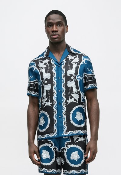 Sada s krátkým rukávem a kraťasy v modré a černé barvě s bílými grafickými potisky zvířat a zdobených motivů. Hladká tkanina, volný střih.