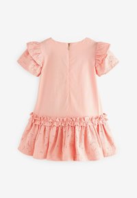Robe rose clair avec des détails en dentelle à œillets sur les manches volantes et l'ourlet. Présente une fermeture éclair dans le dos et une taille froncée pour plus de texture.
