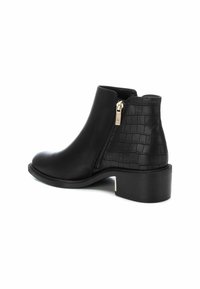 Botas negras hasta el tobillo con un acabado suave y un patrón de cocodrilo texturizado en el tacón. Presentan una cremallera dorada y un tacón bajo. 
