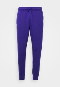 Lila sweatpants gjorda av en bomullsblandning, med resårmidja och dragsko, ribbade manschetter och en liten logotyp på sidan.