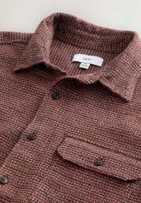 Kaelusega, nööbitud pruun ja valge tekstuuriga särk, millel on esiküljel klapiga tasku ja mustad nööbid, suurus keskmine.