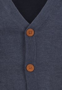 Mörkblå stickad cardigan med V-ringning, försedd med två runda, bruna träknappar som knäppning framtill.