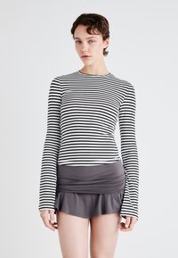 Striped long-sleeve top in black and white, paired with a fitted gray skirt featuring a flared hem. Soft fabric with a smooth texture.