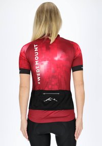 Maillot de cyclisme rouge avec un motif pixélisé, poche arrière noire, manches courtes et design ajusté. Logo "Swedemount" affiché en évidence.
