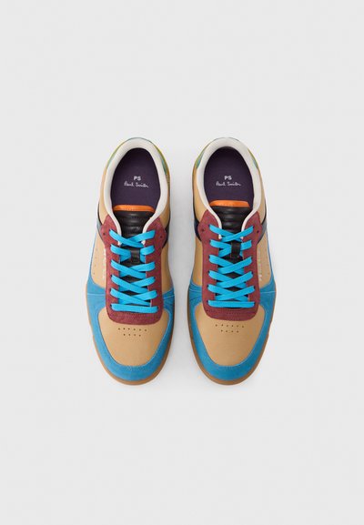 Ζευγάρι πολύχρωμων αθλητικών παπουτσιών με ταμπά, μπλε και μπορντό πάνελ, φωτεινά μπλε κορδόνια και μαύρες μαξιλαρωτές γλώσσες σε λευκό φόντο.