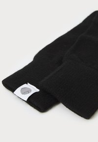 Sorte strikkede handsker med ribbet struktur og et hvidt mærke med bladmønster. Designet er enkelt og funktionelt, med lange manchetter.