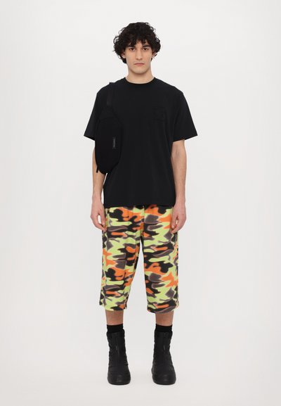 Svart bomull t-skjorte med logo, multicolor camo shorts i grønn, oransje og grå, samt svarte ankelstøvler med tekstur.